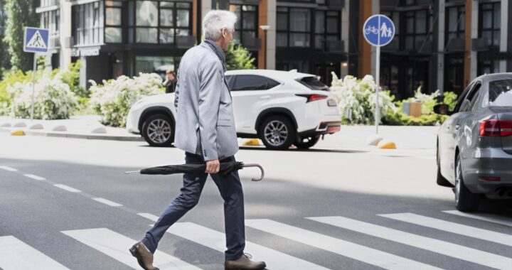 stylish-older-man-city-crossing-street-while-holding-umbrella